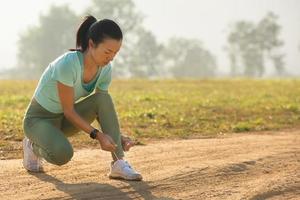 zapatos para correr mujer corredora atando cordones para correr en otoño en el parque forestal. corredor probando zapatos para correr preparándose para correr. jogging girl ejercicio motivación salud y estado físico. foto