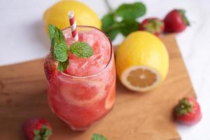 delicioso batido de fresa y limón adornado con fresa fresca y menta en vaso. enfoque suave. hermoso aperitivo rosa fresa, bienestar y concepto de pérdida de peso. foto