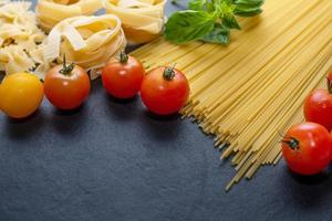 Mixed dried pasta selection on wooden background. composition of healthy food ingredients isolated on black stone background, top view, Flat lay photo