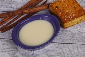 Condenced milk in the bowl with sinnamon and pastry photo