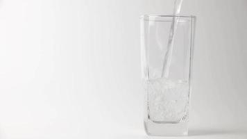 verter la bebida de agua fresca en el vaso sobre fondo gris. verter agua a cámara lenta video