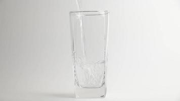 Gießen Sie das Süßwassergetränk in das Glas auf grauem Hintergrund. Wasser gießen video