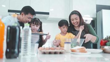 Asian family with children enjoy and happy to cooking in kitchen at home, happiness lifestyle of people who parenting to cook together, smile and joy with eating food at dinner or morning time video