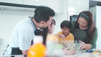 la familia asiática con niños disfruta y feliz de cocinar en la cocina en casa, el estilo de vida feliz de las personas que crían para cocinar juntos, sonríen y se alegran de comer en la cena o en la mañana