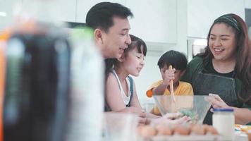 asiatisk familj med barn tycker om och gärna lagar mat i köket hemma, lycka livsstil för människor som förälder att laga mat tillsammans, le och glädje med att äta mat vid middagen eller morgonen video