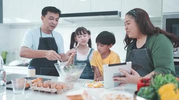 familjeperson som använder digital surfplatta för att lära sig laga mat i köket, barndotter med mamma och pappa livsstil hemma tillsammans, färsk grönsakssallad och måltid för att lära sig att göra meny video