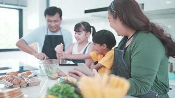 personne de la famille utilisant une tablette numérique pour apprendre à cuisiner un aliment dans la cuisine, enfant fille avec mère et père à la maison ensemble, salade de légumes frais et repas pour apprendre à faire un menu video