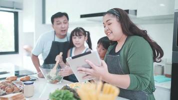 personne de la famille utilisant une tablette numérique pour apprendre à cuisiner un aliment dans la cuisine, enfant fille avec mère et père à la maison ensemble, salade de légumes frais et repas pour apprendre à faire un menu video