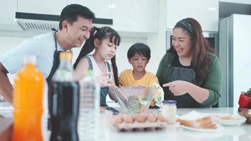 Asian family with children enjoy and happy to cooking in kitchen at home, happiness lifestyle of people who parenting to cook together, smile and joy with eating food at dinner or morning time