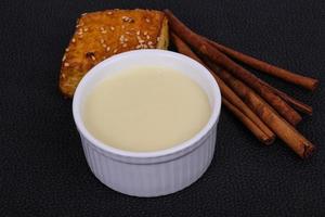 Condenced milk in the bowl with sinnamon and pastry photo