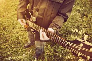 Young man playing on the guitar outdoors. Vintage, music photo