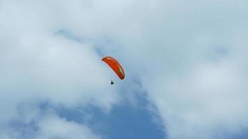 One paraglider flying through the blue sky with the white clouds photo