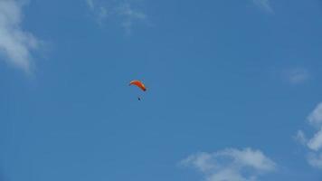 un parapente volando por el cielo azul con nubes blancas foto