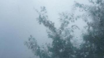 The glass window covered by the rain droplets and waterfall in the rainy day photo