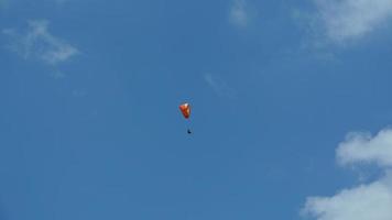 One paraglider flying through the blue sky with the white clouds photo