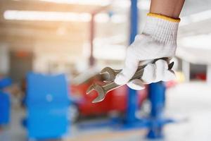 Car mechanic holding wrench at the car repair garage photo