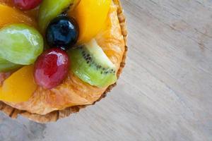 close up danish pastry with fruit on wood table photo