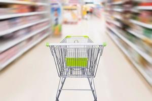 shopping cart with abstract motion blur supermarket discount store aisle and product shelves interior defocused background photo