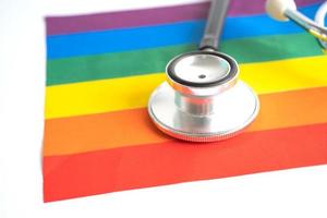 Black stethoscope on rainbow flag background, symbol of LGBT pride month  celebrate annual in June social, symbol of gay, lesbian, bisexual, transgender, human rights and peace. photo