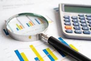 Magnifying glass on charts graphs paper. Financial development, Banking Account, Statistics, Investment Analytic research data economy, Stock exchange trading, Business office company meeting concept. photo