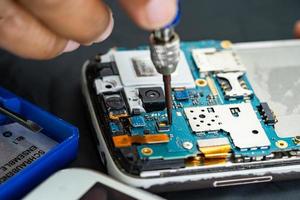 Technician repairing inside of mobile phone by soldering iron. Integrated Circuit. the concept of data, hardware, technology.