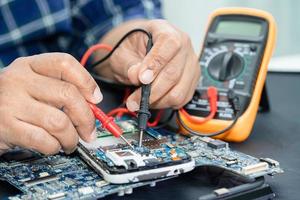 Technician repairing inside of mobile phone by soldering iron. Integrated Circuit. the concept of data, hardware, technology. photo