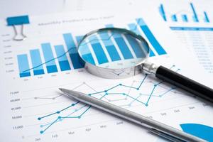 Magnifying glass on charts graphs paper. Financial development, Banking Account, Statistics, Investment Analytic research data economy, Stock exchange trading, Business office company meeting concept. photo