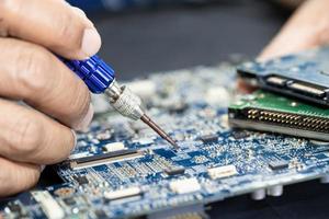 Technician repairing inside of printed circuit board PCB by soldering iron. Integrated Circuit. the concept of data, hardware, technician and technology. photo