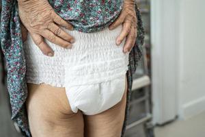 Paciente asiático mayor o mayor de la mujer de la señora mayor que lleva el pañal de la incontinencia en la sala del hospital de enfermería, concepto médico fuerte sano. foto