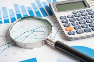 Magnifying glass on charts graphs paper. Financial development, Banking Account, Statistics, Investment Analytic research data economy, Stock exchange trading, Business office company meeting concept. photo