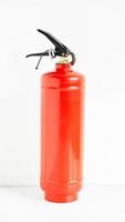 Red fire extinguisher on a white wall background photo