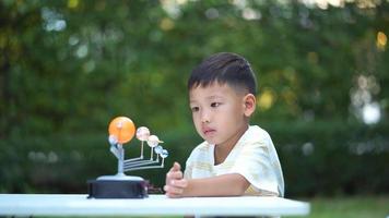 Asian boy Living Solar System Toys, Home Learning Equipment, during new normal change after coronavirus or post covid-19 outbreak pandemic situation photo