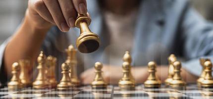 Person holding golden chess pieces to run a game, conceptual image of businessman playing chessboard compared to managing a business on risk, chart graphics showing financial flows. photo