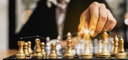 persona que tiene piezas de ajedrez doradas para ejecutar un juego, imagen conceptual de un hombre de negocios que juega al tablero de ajedrez en comparación con la gestión de un negocio en riesgo, gráficos de gráficos que muestran los flujos financieros. foto