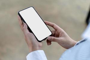 la pantalla en blanco del teléfono inteligente, la persona que sostiene el teléfono inteligente y mira la pantalla en blanco, la pantalla de maqueta para su posterior edición se puede usar en una variedad de tareas. copie el espacio foto