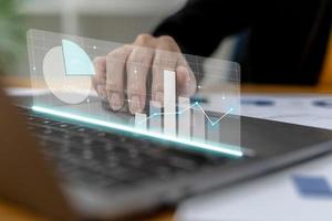 Close-up businesswoman hand using a laptop touchpad to open a financial report, a graphic showing financial and numerical growth data. The concept of financial management to grow and be profitable. photo