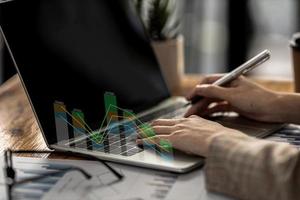 Close-up businesswoman hand using a laptop touchpad to open a financial report, a graphic showing financial and numerical growth data. The concept of financial management to grow and be profitable. photo