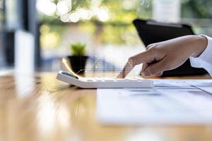 Businesswoman presses a calculator to check data on documents, company financial reports, graphics showing financial and numerical growth data. Financial management to grow and be a profitable concept photo