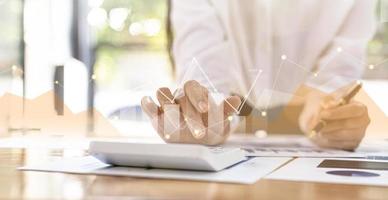 Businesswoman presses a calculator to check data on documents, company financial reports, graphics showing financial and numerical growth data. Financial management to grow and be a profitable concept photo