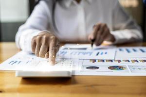 Businesswoman presses a calculator to check data on documents, company financial reports, graphics showing financial and numerical growth data. Financial management to grow and be a profitable concept photo