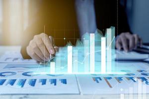 A business man examines data on financial documents, company financial reports, graphics showing financial and numerical growth data. The concept of financial management to grow and be profitable. photo