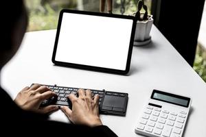 Tablet blank screen, person looking at blank tablet screen and typing on keyboard, screen mockup for further editing can be used for a variety of tasks. copy space. photo