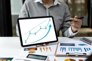 dos empresarios que usan una tableta para ver los informes financieros de la empresa, gráficos que muestran datos financieros y de crecimiento numérico. el concepto de gestión financiera para crecer y ser rentable. foto