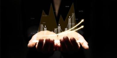 Hologram of financial graphs displayed on a person's hand, graphic charts and fluctuations in financial data, showing business growth. Business strategy. Digital marketing. digital business hologram. photo