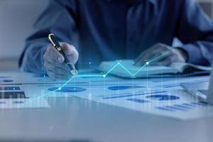A business man examines data on financial documents, company financial reports, graphics showing financial and numerical growth data. The concept of financial management to grow and be profitable. photo