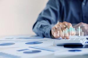 A business man examines data on financial documents, company financial reports, graphics showing financial and numerical growth data. The concept of financial management to grow and be profitable. photo