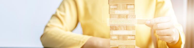 A woman plays a game of wooden blocks that are building blocks, she is picking up a block of wood from a row, like managing a business on risk, management to make the business grow and be profitable. photo