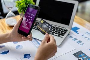 Person holding a smartphone at the screen of an online payment website, using a smartphone to pay for goods via credit card online. Concept of using smartphones to pay for products via credit card. photo