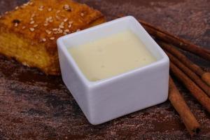 Condenced milk in the bowl with sinnamon and pastry photo