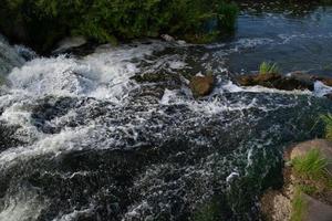 una pequeña cascada de río en un brillante día soleado de verano. foto